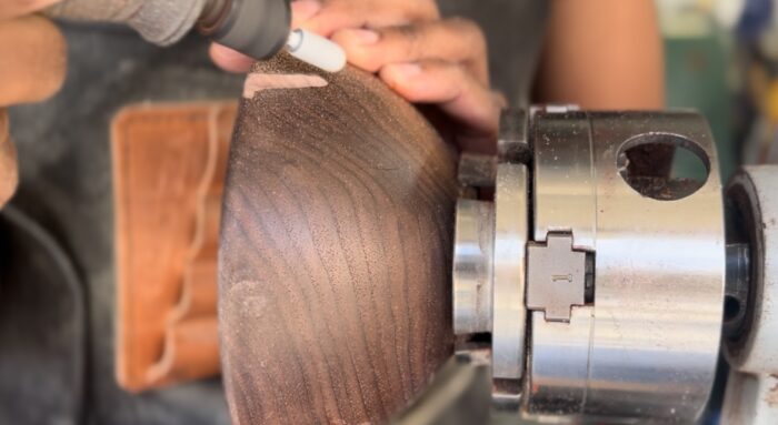 Char uses a rotary tool to add texture to a bowl attached to the lathe.