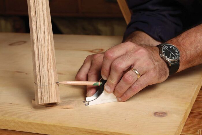 A tool is used to draw a line at a consistent level on the bottom of the chair leg. 