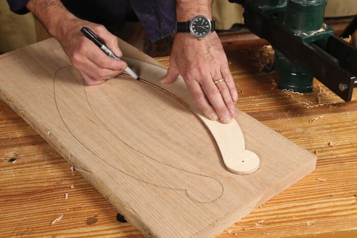 A template is being used to trace around creating lines that will eventually be sawn out as the arms of the chair. 