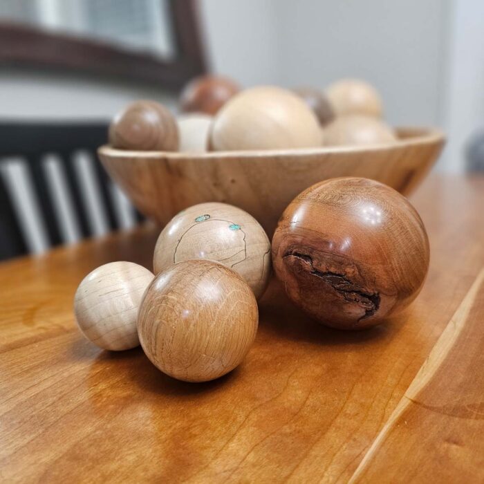 Wooden spheres on a table. They're highly polished and varying sizes. 