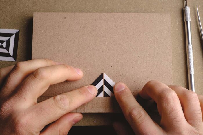 Vasko holds two striped triangles against each other along a strip of MDF.