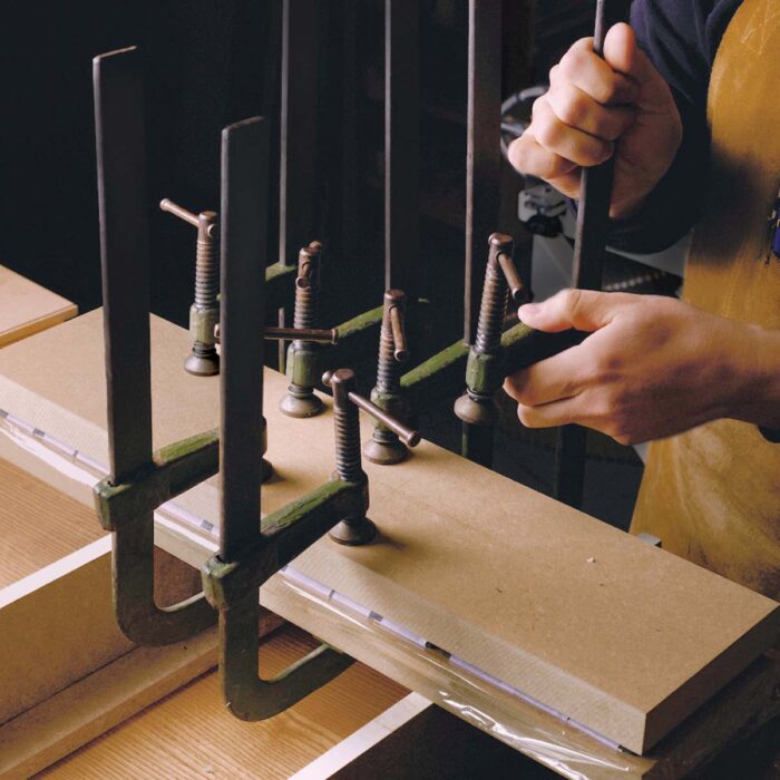 Several F-style clamps apply presssure to two 3/4 MDF cauls that sandwich the box sides in between them.