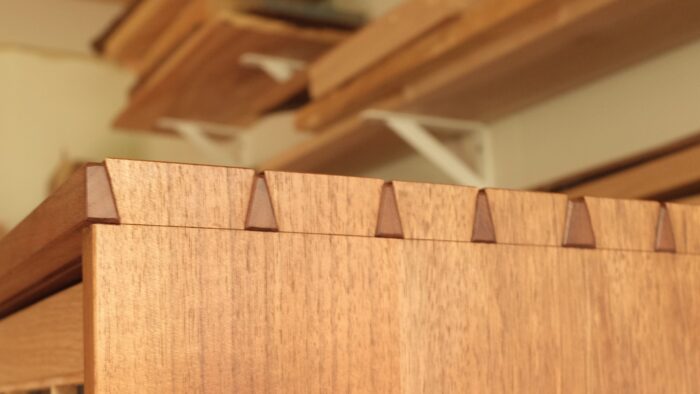 A dovetailed case piece sits in a shop, with the photo focusing on the dovetails. 