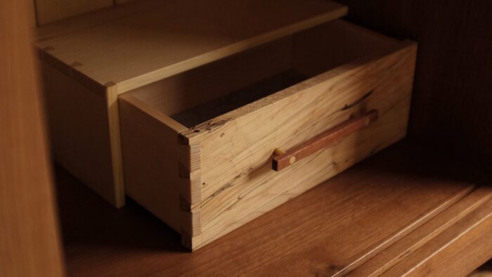 A photo of a dovetailed drawer, with raking light to accentuate the handle and dovetails.