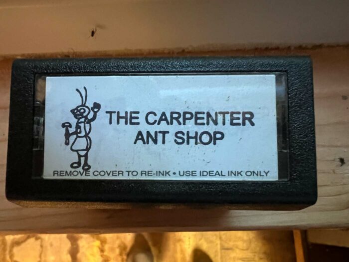 A sign hung above a door that reads "The Carpenter Ant Shop"